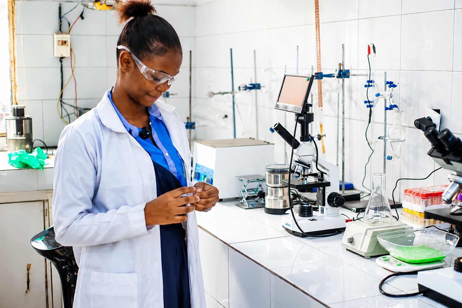 Élève en blouse observant au microscope numérique